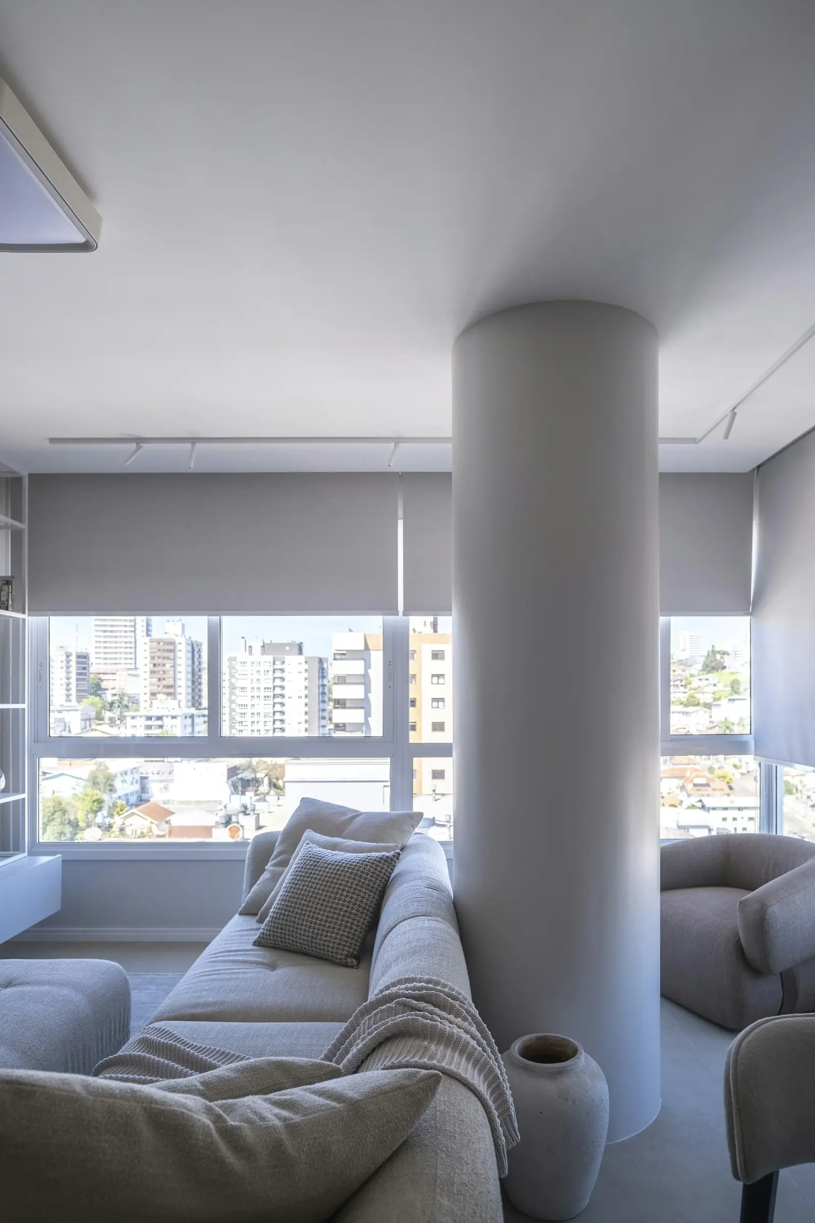 Living luminoso con cortinas roller en los ventanales