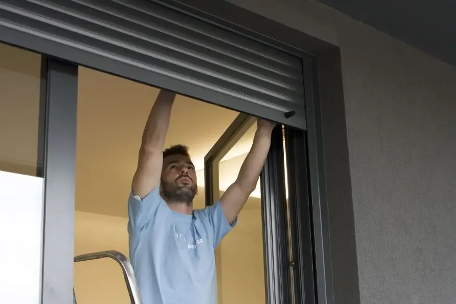 Técnico instalando una cortina de enrollar en una ventana